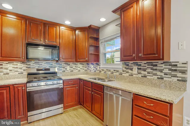 a kitchen with stainless steel appliances granite countertop wooden cabinets stove top oven and sink