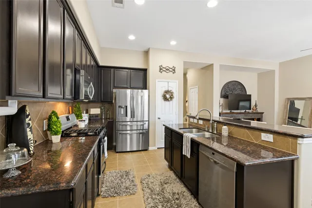 a kitchen with stainless steel appliances granite countertop a refrigerator a stove a sink and a refrigerator