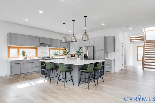 a kitchen with stainless steel appliances kitchen island granite countertop a table chairs sink and cabinets