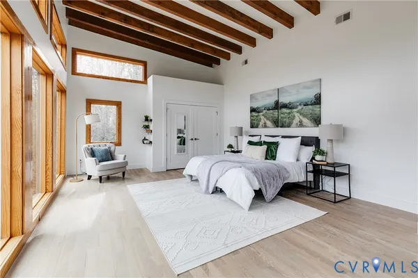 a spacious bedroom with a bed a table and large windows