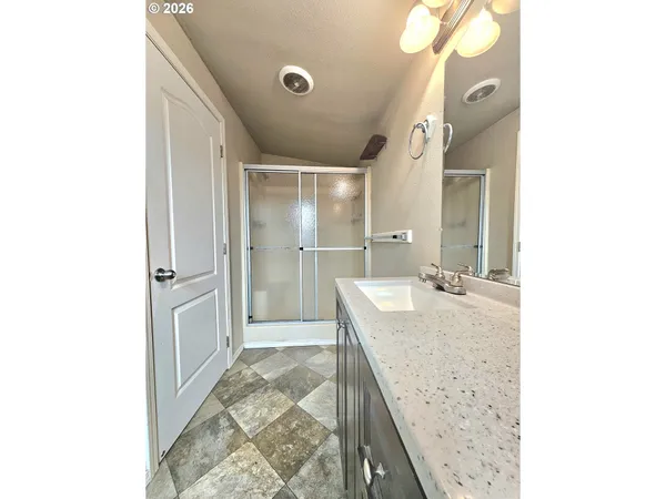 a bathroom with a granite countertop sink a mirror and shower