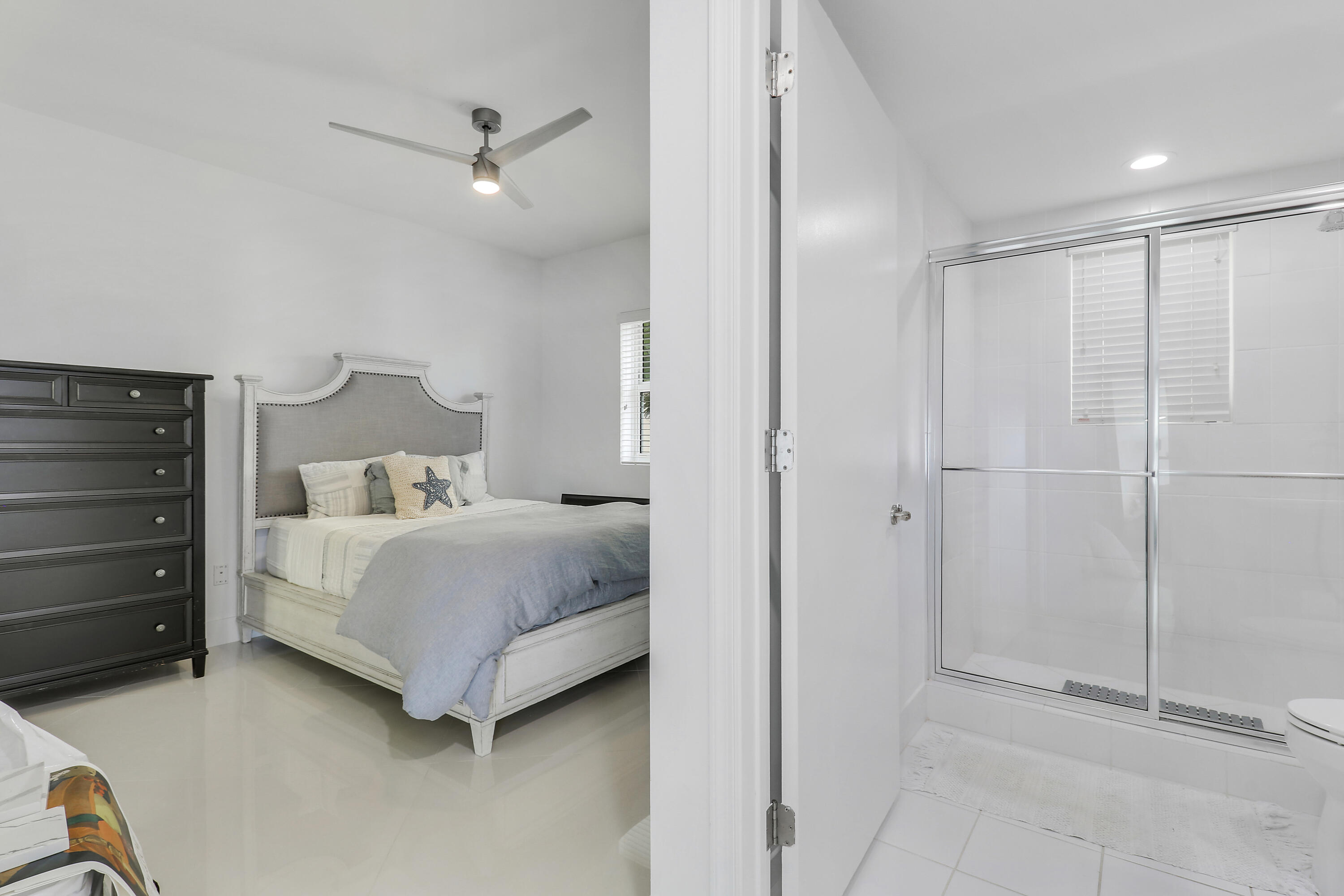2640 Lake Shore Drive, Unit 307 Riviera Beach, FL 33404 - Photo 36 of 44 a bedroom with a bed and a ceiling fan