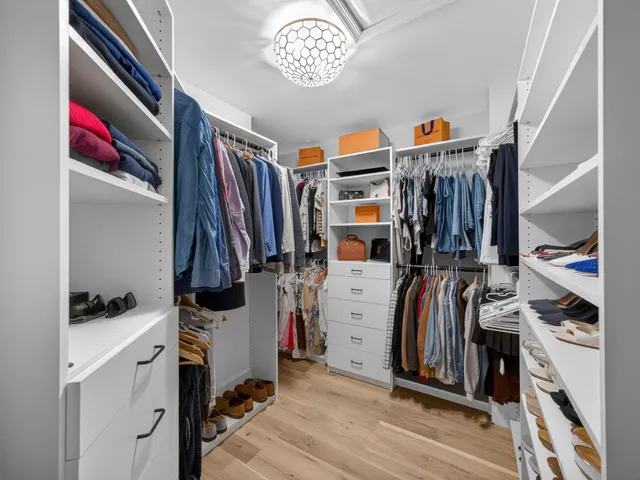 a view of walk in closet with clothes and shoes