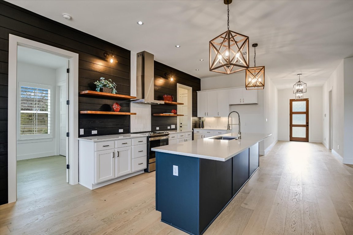 935 Wesley Ridge Drive Spicewood, TX 78669 - Photo 13 of 40 a kitchen with stainless steel appliances granite countertop a sink a stove and a wooden floors