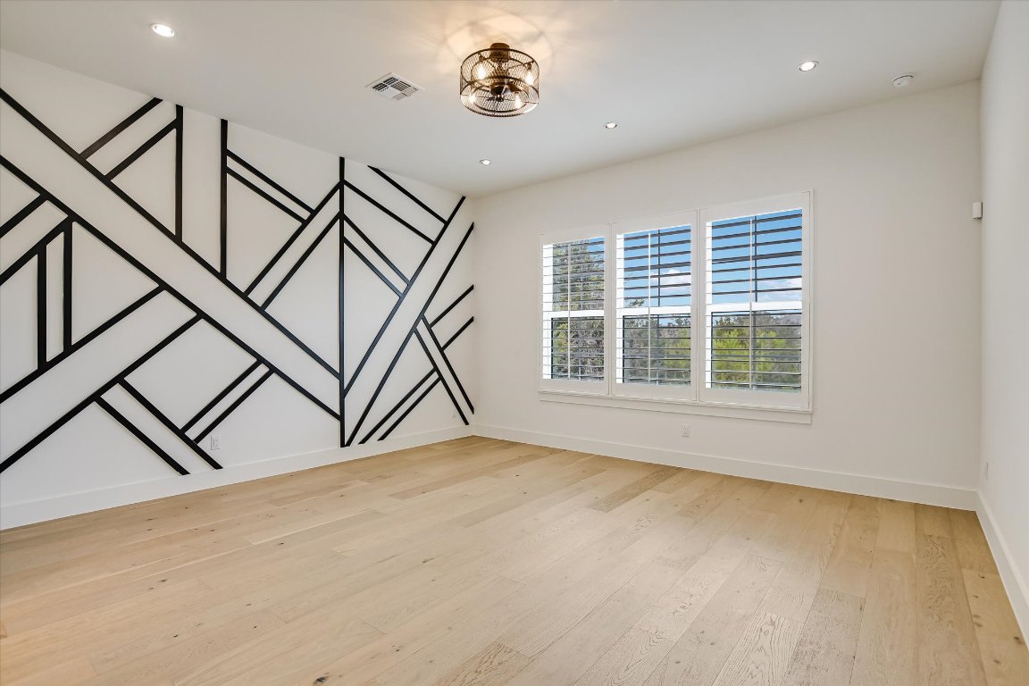 935 Wesley Ridge Drive Spicewood, TX 78669 - Photo 21 of 40 Privately positioned within the home, the primary bedroom offers good natural light, a comfortable layout, and space for a full bedroom arrangement. The accent wall adds visual interest while keeping the room versatile and easy to personalize.