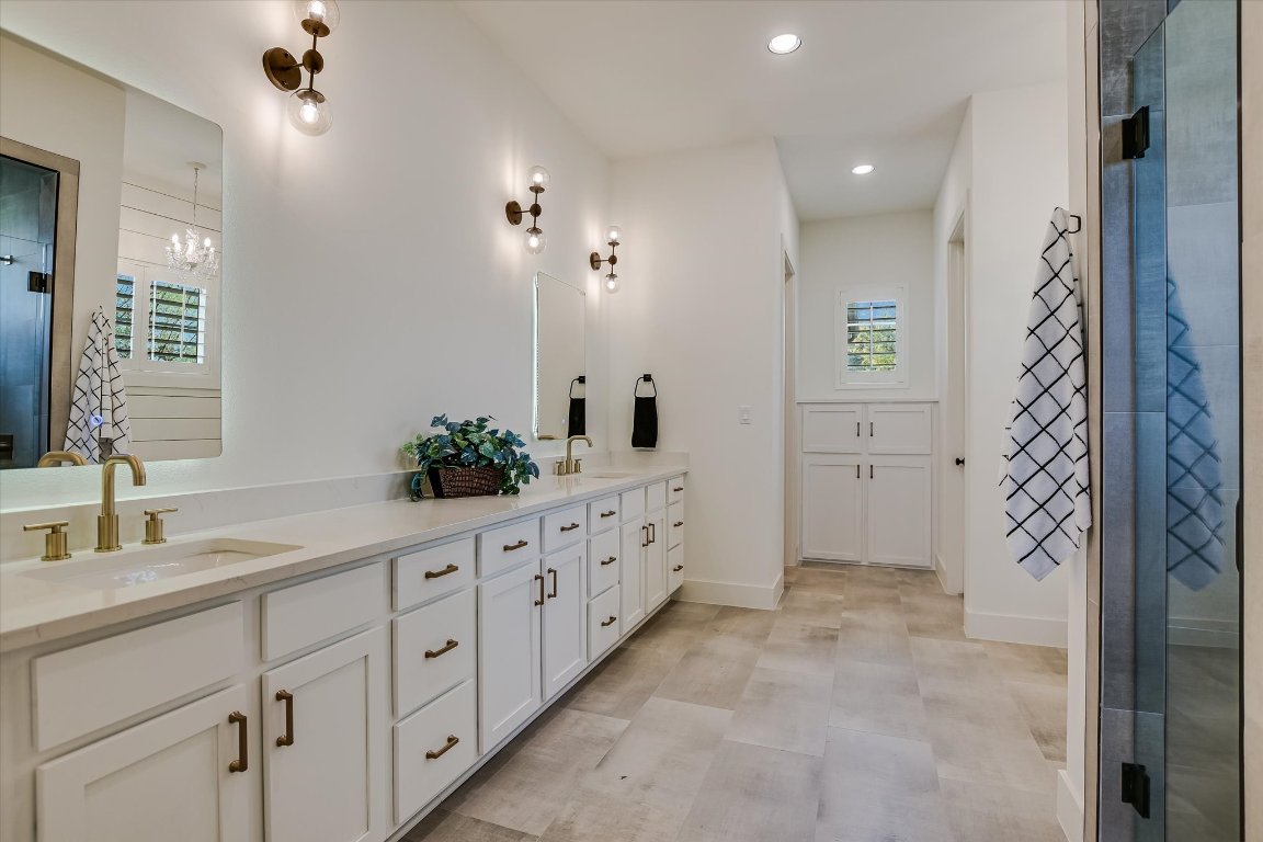 935 Wesley Ridge Drive Spicewood, TX 78669 - Photo 22 of 40 The primary bath features a long double vanity with backlit mirrors, generous counter space, and warm brass fixtures. A separate shower and an easy, straightforward layout make it well suited for everyday routines.