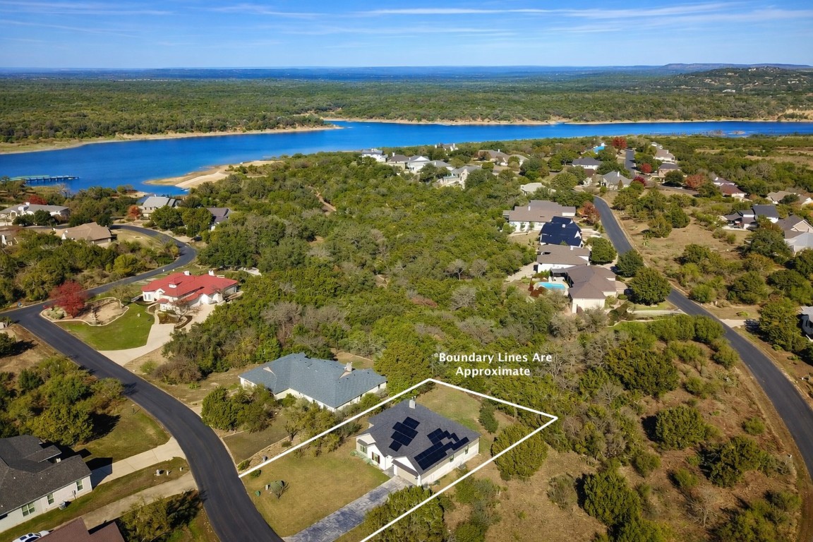 935 Wesley Ridge Drive Spicewood, TX 78669 - Photo 30 of 40 This aerial view shows the home’s placement within Ridge Harbor, with approximate boundary lines outlining the lot. The setting offers a sense of space and privacy, while Lake Travis sits just beyond the tree line, reinforcing how close the home is to the lake.