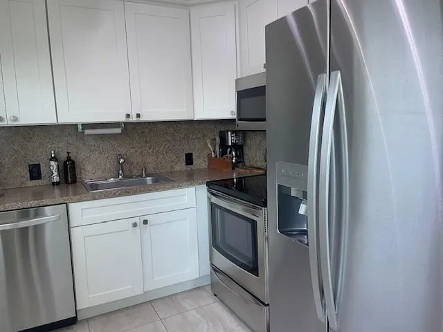 a kitchen with white cabinets and stainless steel appliances