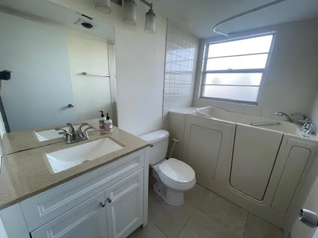a bathroom with a granite countertop sink toilet and mirror