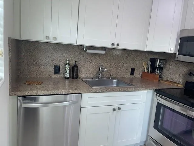 a kitchen with granite countertop white cabinets and a sink
