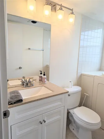 a bathroom with a granite countertop toilet sink and mirror