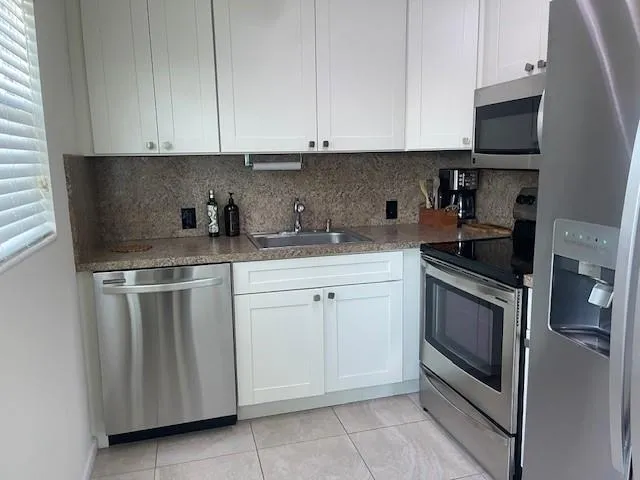 a kitchen with granite countertop white cabinets and stainless steel appliances