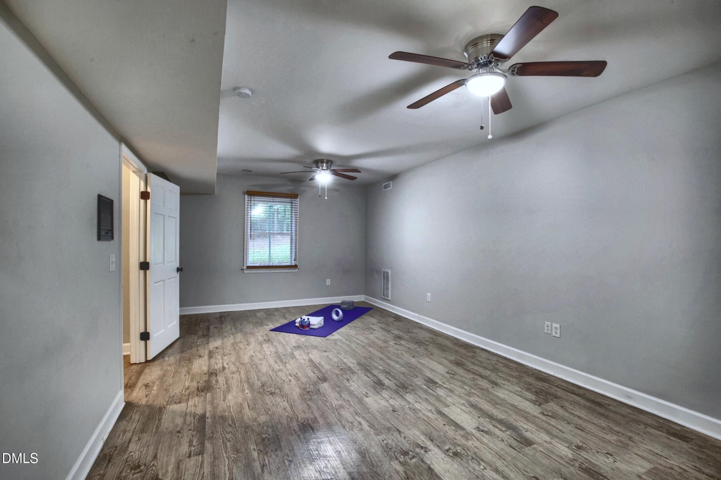 2329 Win Road Garner, NC 27529 - Photo 62 of 90 Room featuring wood-finish flooring, light gray walls, two ceiling fans with integrated lighting, and a window with blinds