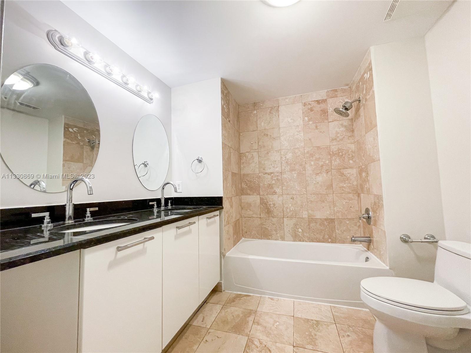 3339 Virginia Street, Unit PH26 Miami, FL 33133 - Photo 15 of 19 a bathroom with a granite countertop sink a toilet a mirror and bathtub