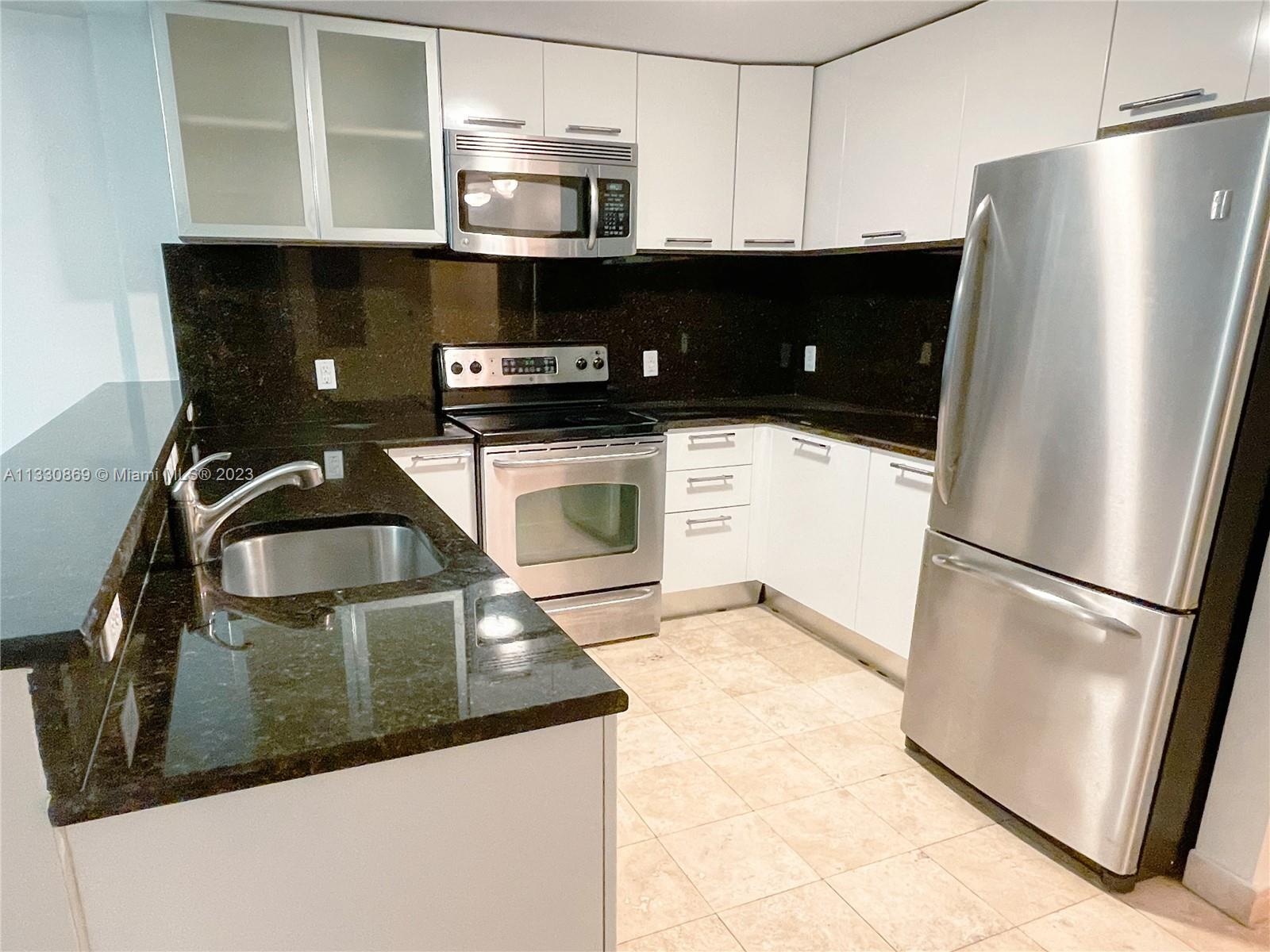 3339 Virginia Street, Unit PH26 Miami, FL 33133 - Photo 6 of 19 a kitchen with stainless steel appliances a refrigerator a sink a stove and white cabinets
