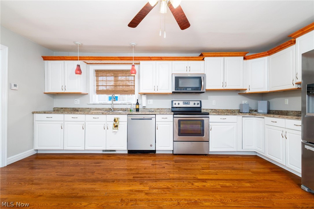 165 9th Street Wellsburg, WV 26070 - Photo 18 of 37 Kitchen with stainless steel appliances, white cabinetry, ceiling fan, decorative light fixtures, and light stone counters