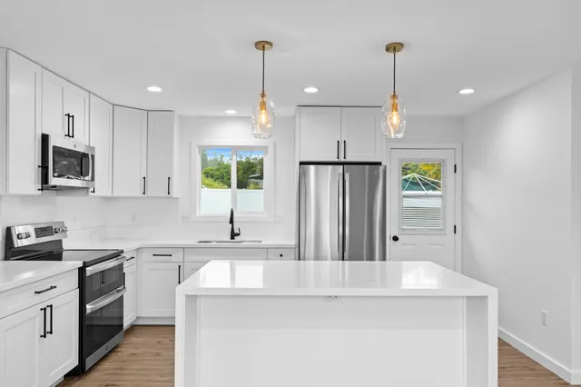 a kitchen with stainless steel appliances granite countertop a sink a stove and a refrigerator