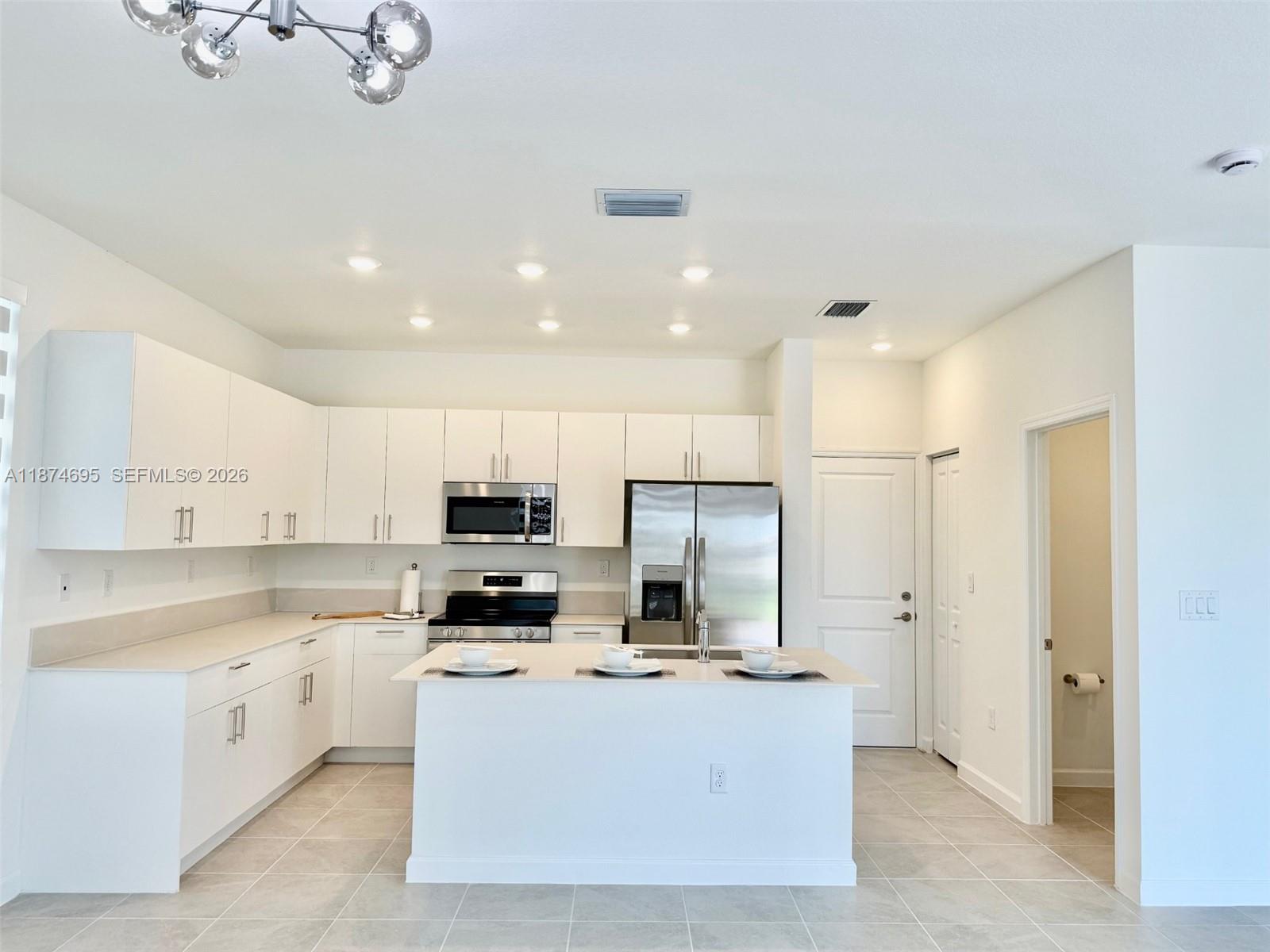 2600 Southeast 25th Street Homestead, FL 33035 - Photo 22 of 61 a kitchen with kitchen island a refrigerator a stove a sink and white cabinets