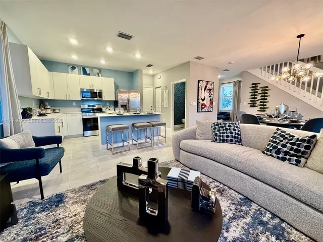 a living room with furniture kitchen view and a wooden floor