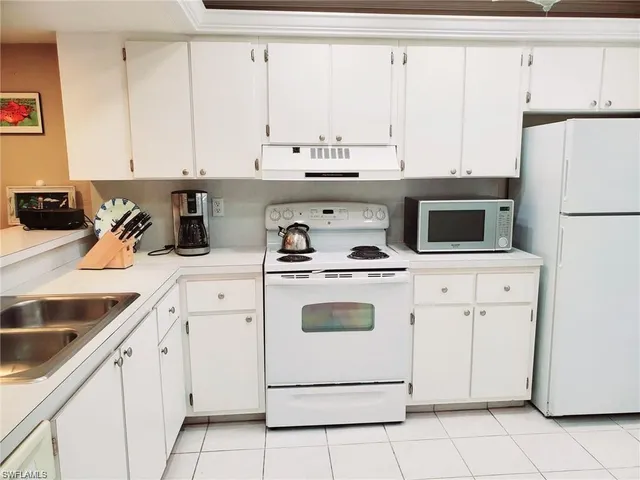 a kitchen with white cabinets and white appliances