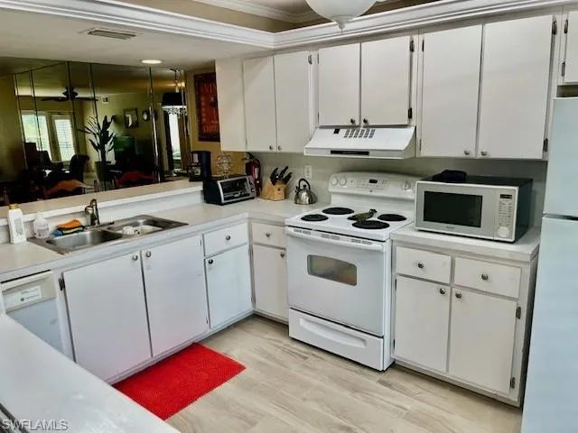 a kitchen with white cabinets a sink and white appliances