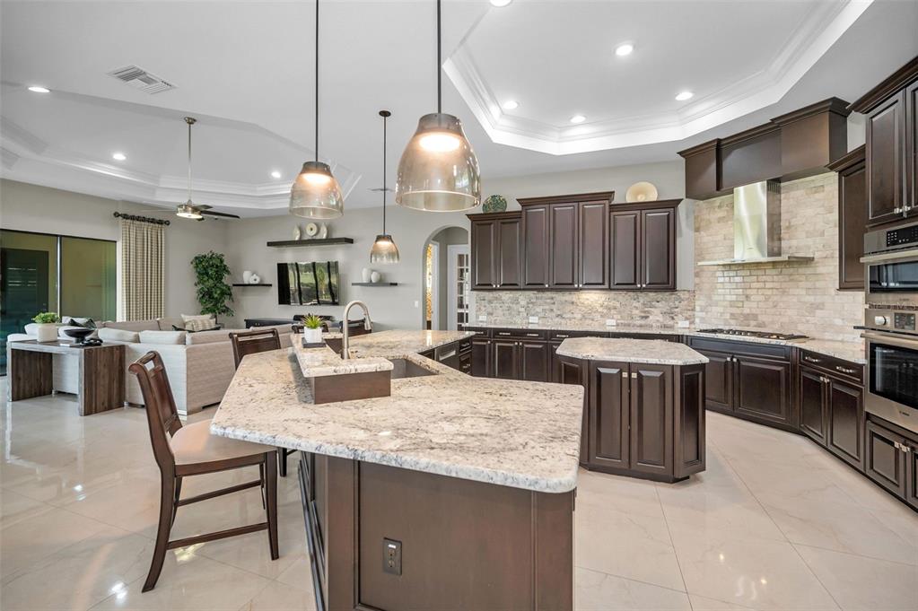 9829 Milano Drive Trinity, FL 34655 - Photo 29 of 100 a kitchen with kitchen island granite countertop a stove a sink a oven a dining table and chairs