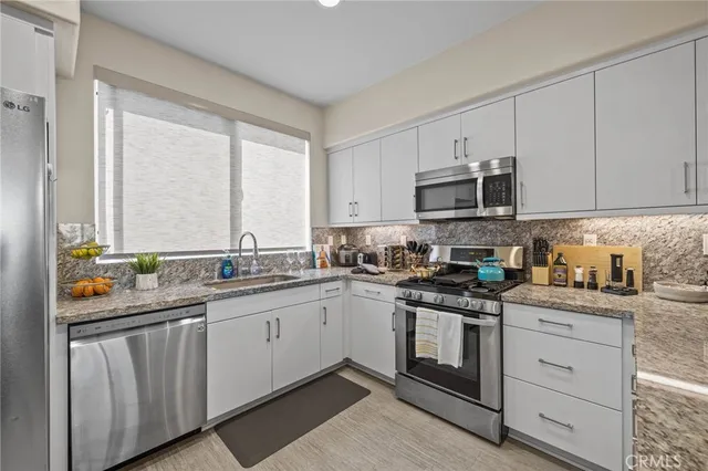 a kitchen with stainless steel appliances granite countertop white cabinets a sink and dishwasher next to a window