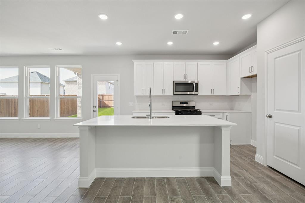 529 Magellan Road Seagoville, TX 75159 - Photo 3 of 37 a kitchen with a sink a counter top space cabinets and stainless steel appliances