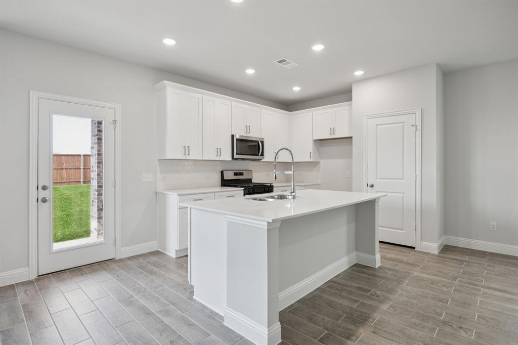 529 Magellan Road Seagoville, TX 75159 - Photo 4 of 37 a kitchen with a stove a sink and a microwave