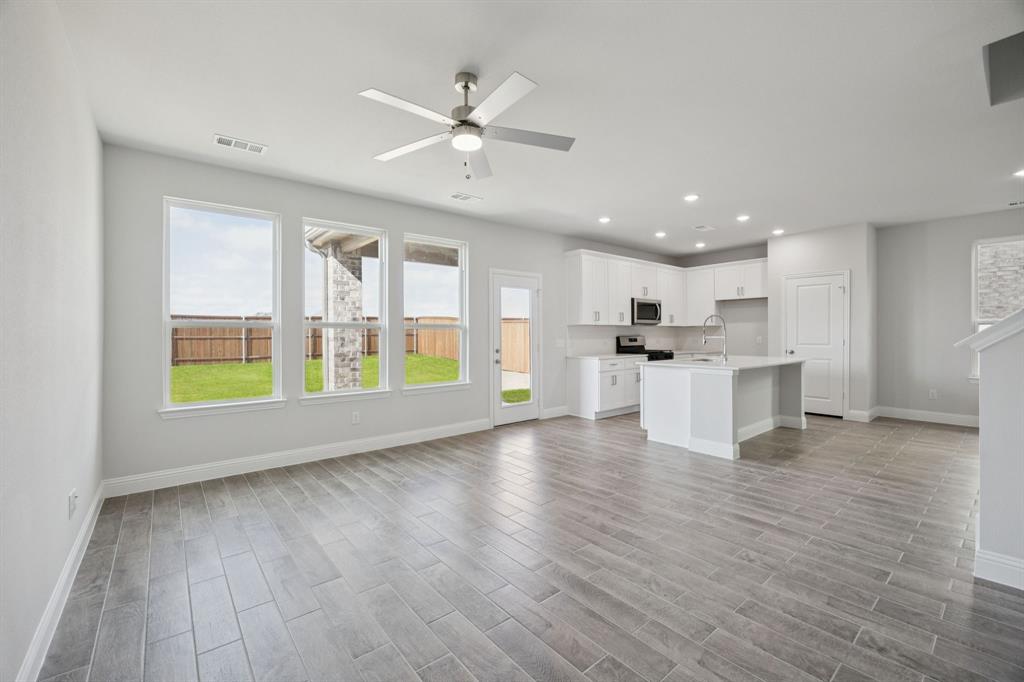 529 Magellan Road Seagoville, TX 75159 - Photo 6 of 37 a view of an empty room with wooden floor and a kitchen