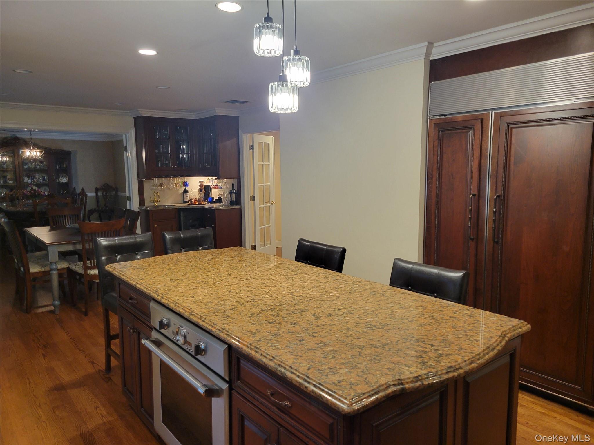 51 Bay Road Huntington Bay, NY 11743 - Photo 11 of 42 Kitchen with a breakfast bar area, a chandelier, dark brown cabinetry, hanging light fixtures, and ornamental molding