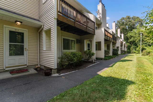 a view of a house with brick walls and a yard with plants