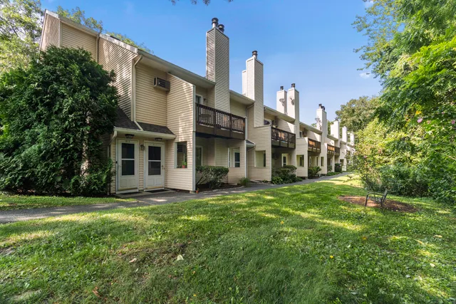 a view of a white house with a big yard and large trees