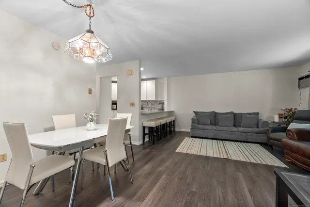 a living room with a dining table a couches a fireplace and a chandelier