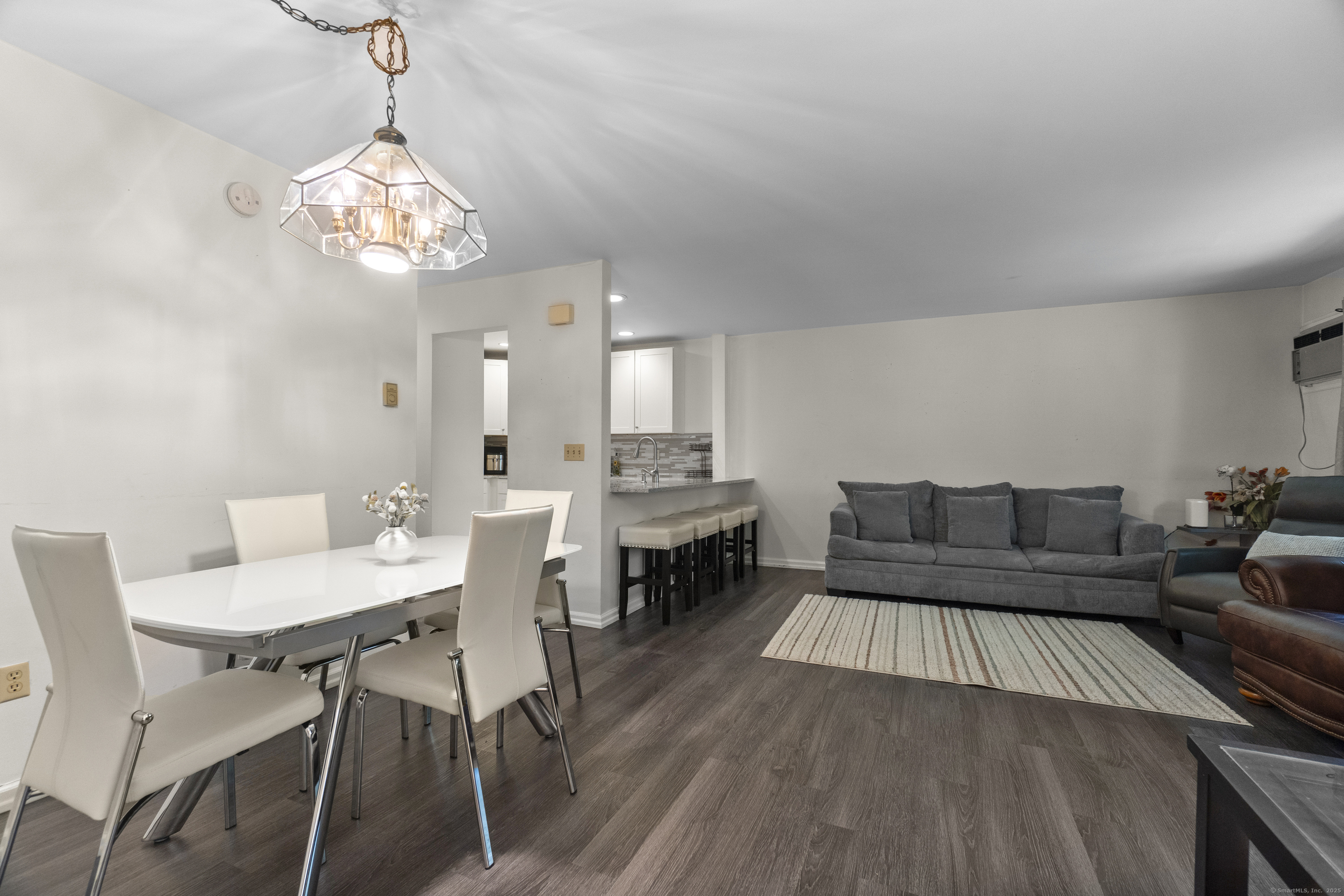 8 Rose Lane, Unit 105 Danbury, CT 06811 - Photo 4 of 20 a living room with a dining table a couches a fireplace and a chandelier