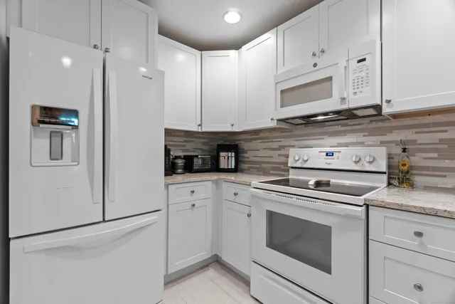 a kitchen with stainless steel appliances granite countertop white cabinets and stove a refrigerator with white cabinets