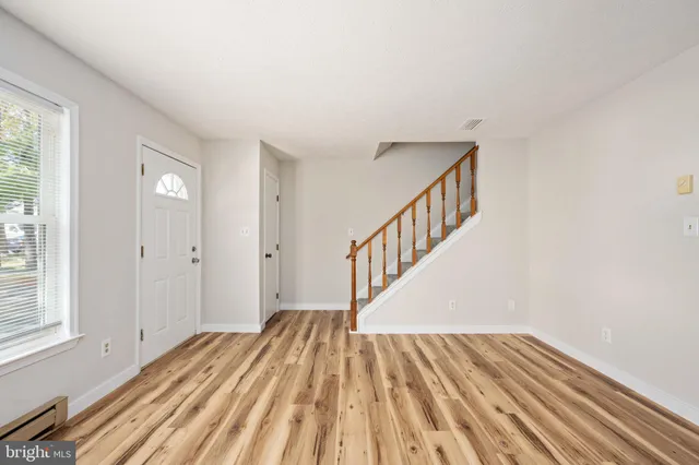 a view of an empty room with wooden floor and stairs