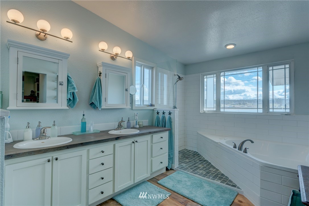 2575 West Beach Road Oak Harbor, WA 98277 - Photo 14 of 25 a bathroom with double vanity sink a mirror and a bathtub