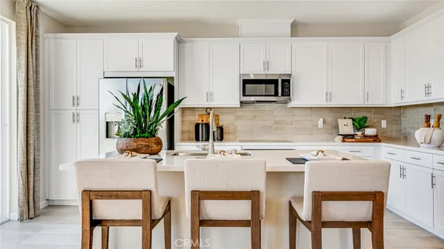 a kitchen with stainless steel appliances a white table and chairs in it