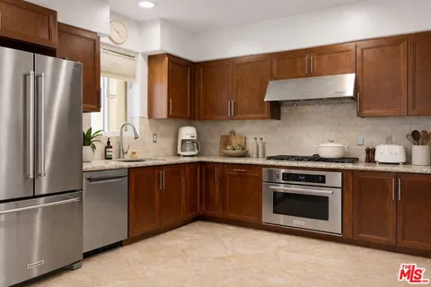 a kitchen with stainless steel appliances granite countertop a refrigerator stove top oven a sink and dishwasher