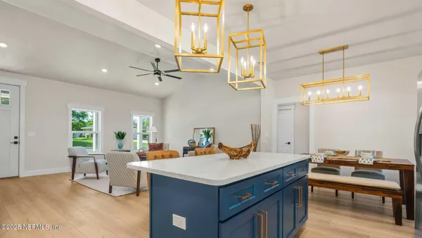 a open dining room with stainless steel appliances kitchen island granite countertop a table chairs and a view of living room