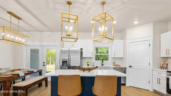 a kitchen with stainless steel appliances a refrigerator a stove a sink dishwasher a dining table and chairs with wooden floor