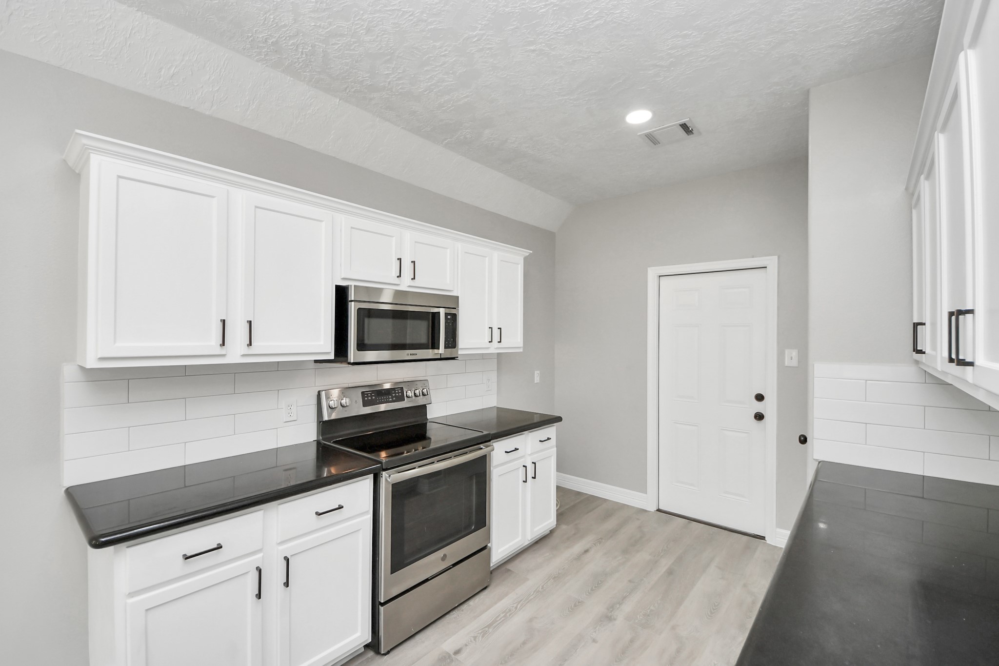 1105 East Kyle Road Clute, TX 77531 - Photo 11 of 44 This home features a modern kitchen with sleek black countertops, white cabinetry, and stainless steel appliances.