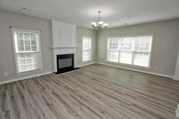 a view of an empty room with wooden floor fireplace and a window