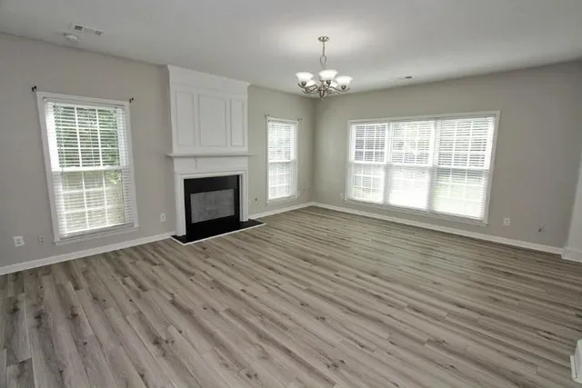 a view of an empty room with wooden floor fireplace and a window