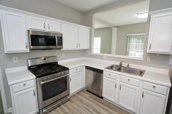 a kitchen with cabinets stainless steel appliances a sink and a window