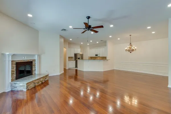 a view of an empty room with kitchen and fireplace
