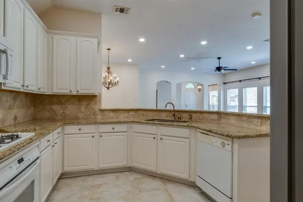 a kitchen with white cabinets sink and stove