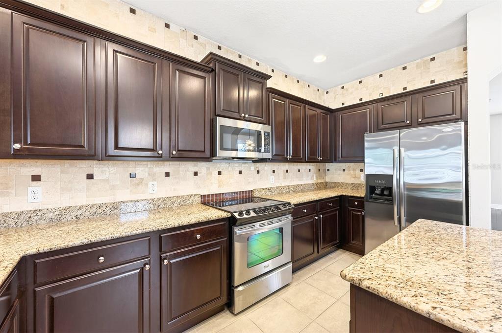 918 Seburn Road Apopka, FL 32703 - Photo 8 of 34 a kitchen with stainless steel appliances granite countertop wooden cabinets and a stove top oven