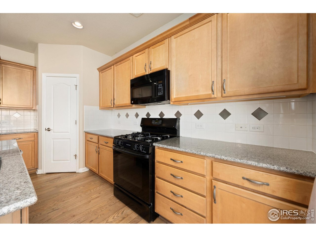 4874 Sandy Ridge Avenue Firestone, CO 80504 - Photo 6 of 35 a kitchen with granite countertop white cabinets and black appliances